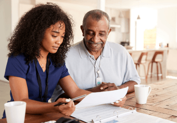 A caregiver and an older man review paperwork together.
