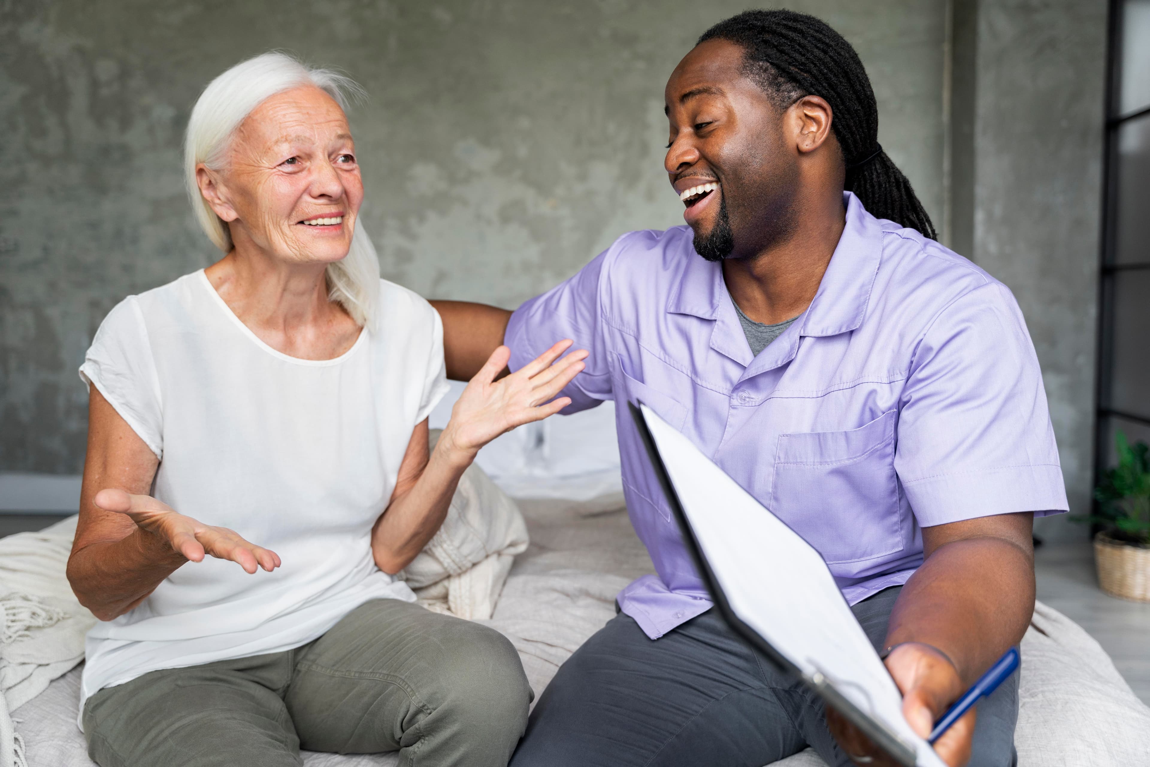 An older woman and a caregiver enjoy a friendly conversation.